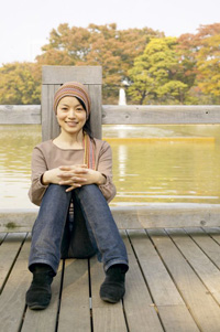 photo of woman sitting on dock at pond